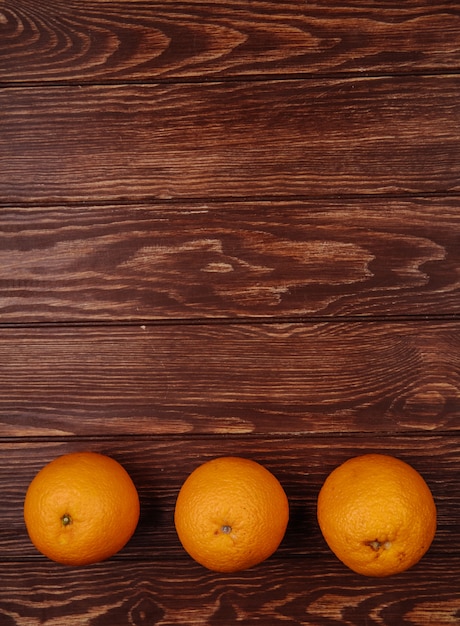 Free Photo top view of fresh ripe oranges lined in a row on wood with copy space