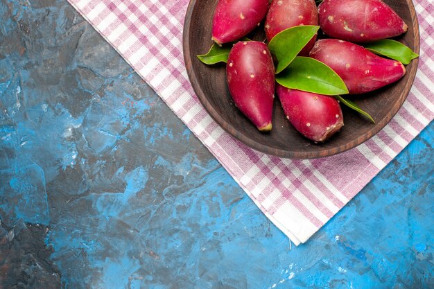 Top view fresh ripe plums inside plate on a blue background