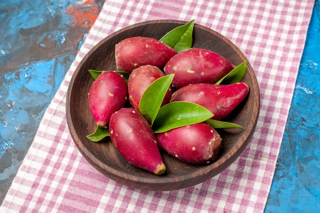 Top view fresh ripe plums inside plate on the blue background