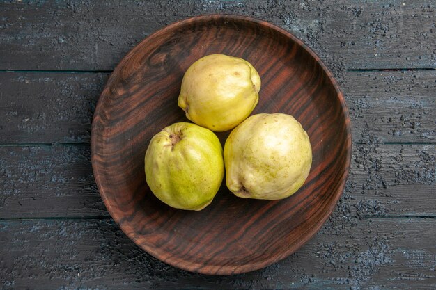 Top view fresh ripe quinces sour fruits inside plate on dark-blue rustic desk plant fruit tree ripe fresh