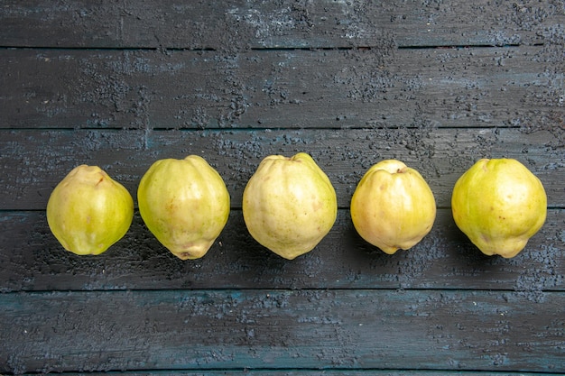 Free photo top view fresh ripe quinces sour fruits lined on a dark-blue rustic desk plant fruit tree ripe fresh