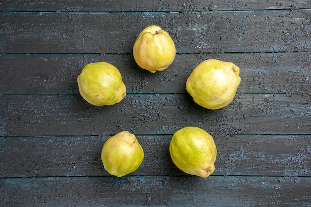 Free photo top view fresh ripe quinces sour fruits lined on dark-blue rustic desk plant fruit tree ripe fresh