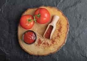 Free photo top view of fresh ripe tomatoes with ketchup and pepper on wooden board over black background.