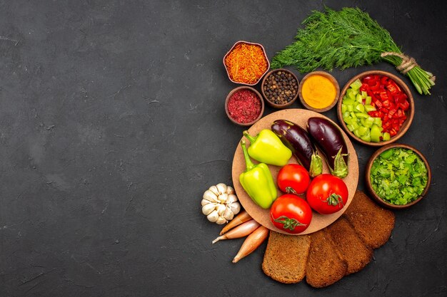 Top view fresh ripe vegetables with greens and dark bread loafs on dark surface salad food meal health vegetable