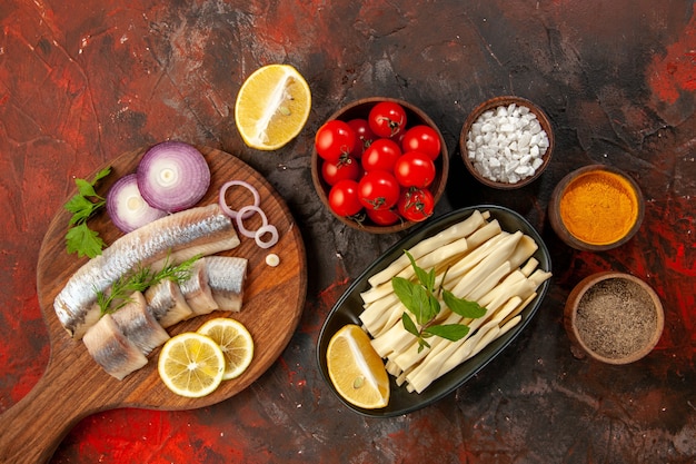 Free photo top view fresh sliced fish with seasonings onion rings and fresh tomatoes on dark background