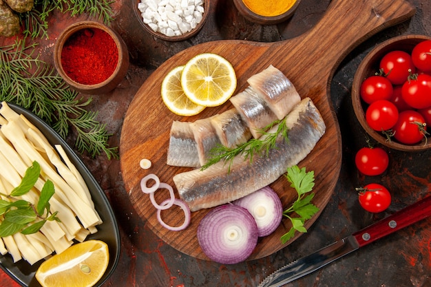 Free photo top view fresh sliced fish with seasonings tomatoes and cheese on dark background