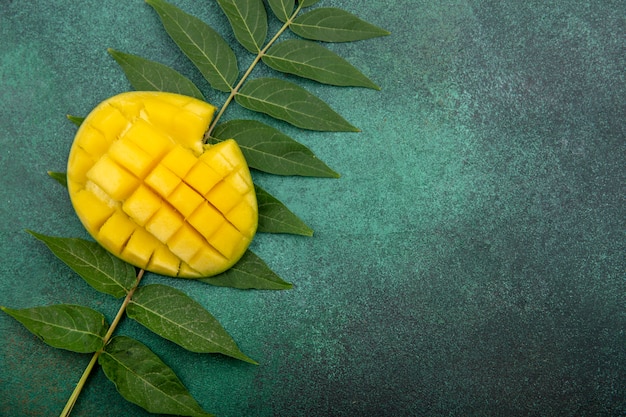 Top view of fresh sliced mango with leaf on green