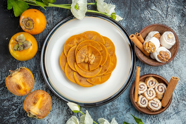 Top view of fresh sliced persimmons with confitures on dark surface