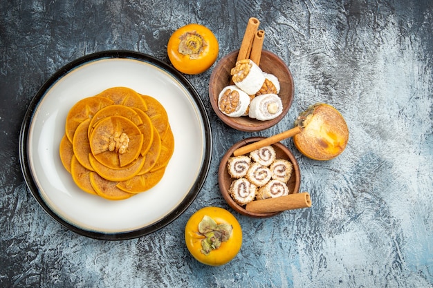 Top view of fresh sliced persimmons with confitures on dark surface