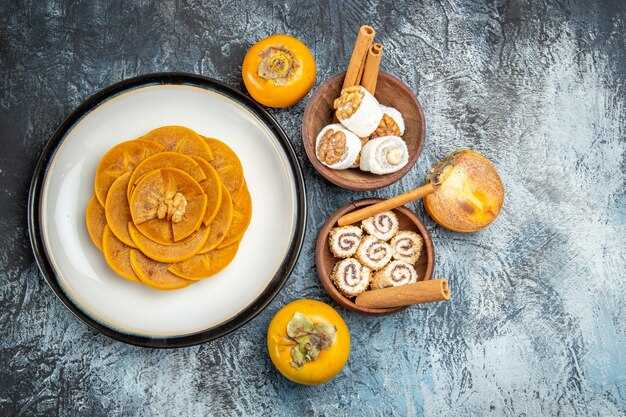 Top view of fresh sliced persimmons with confitures on dark surface