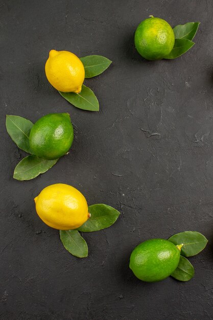 Top view fresh sour lemons on dark-grey table lime citrus fruit