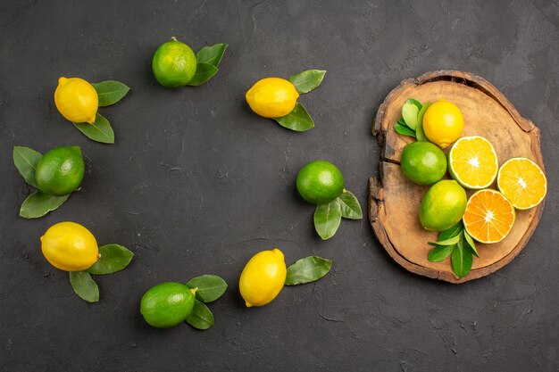 Top view fresh sour lemons on dark-grey table, lime fruit citrus