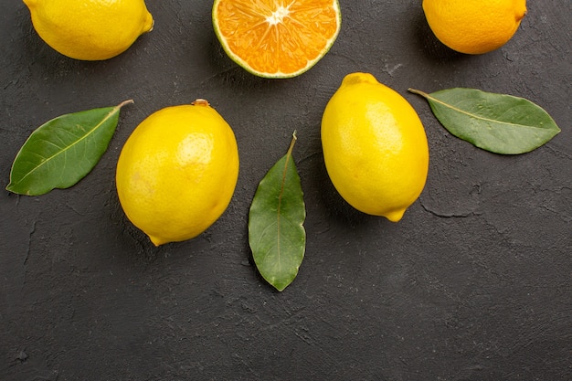 Top view fresh sour lemons lined on dark table, citrus lime yellow fruit