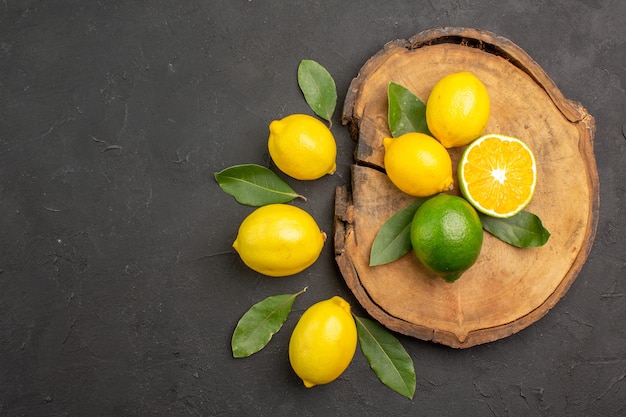 Top view fresh sour lemons with leaves on dark floor fruit lime yellow citrus