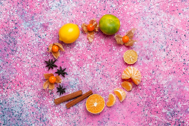 Free photo top view fresh sour tangerines with lemons and cinnamon on light-pink background.