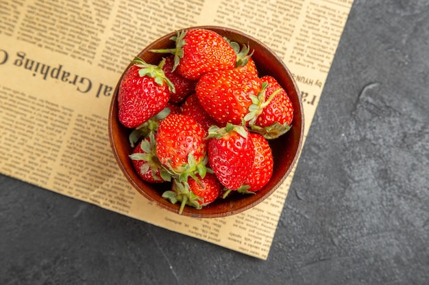 Top view fresh strawberries inside plate around christmas toys on dark background