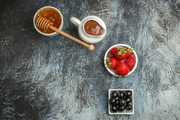 Top view fresh strawberries with olives and honey on dark surface sweet fruit berry