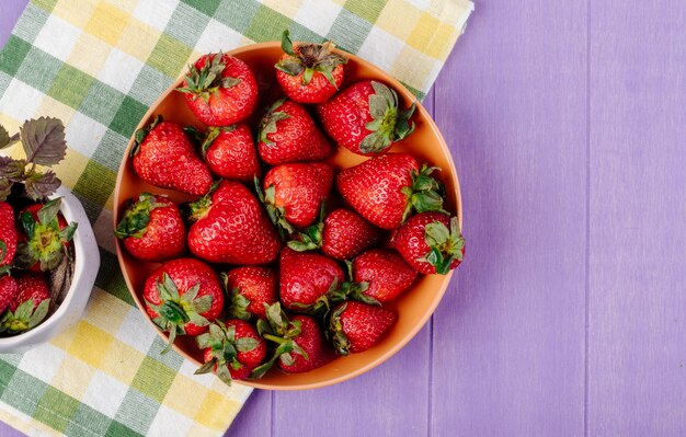 Top view fresh strawberry on a plate on purple background