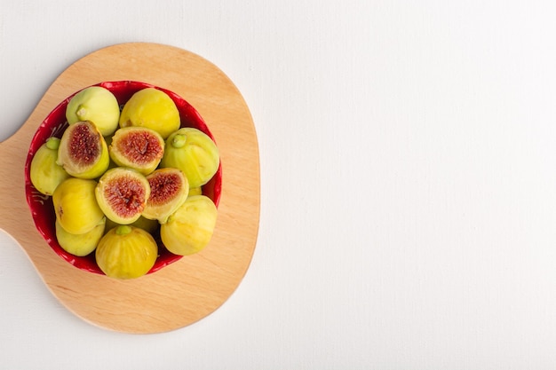 Top view fresh sweet figs delicious fetuses inside red plate on the white desk