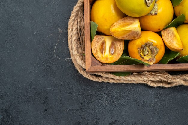 Top view fresh sweet persimmons inside box on the dark table taste ripe fruit