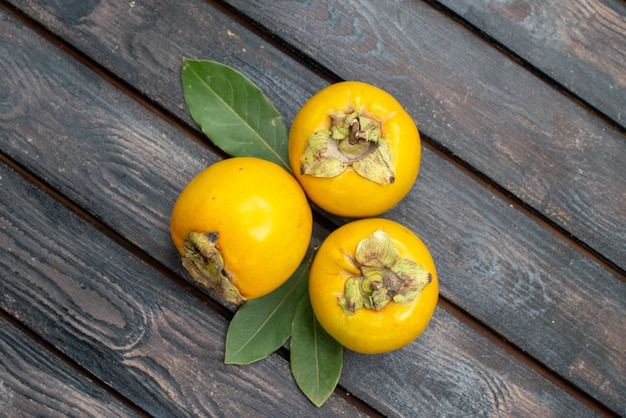 Free photo top view fresh sweet persimmons on wooden rustic table, fruit mellow