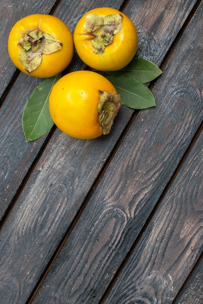 Free photo top view fresh sweet persimmons on wooden rustic table, fruits ripe mellow