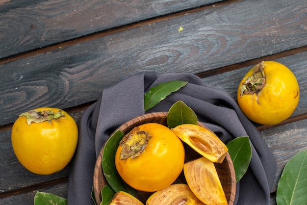 Free photo top view fresh sweet persimmons on a wooden table, fruit ripe mellow