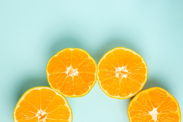 Top view fresh tangerine slices lined on light-blue background