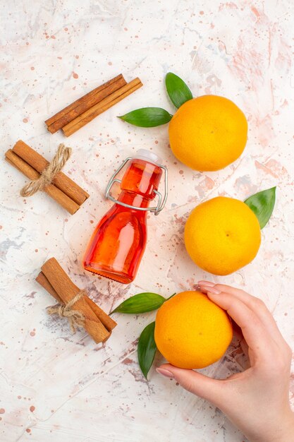 Top view fresh tangerines cinnamon sticks tangerine in female hand bottle on bright surface