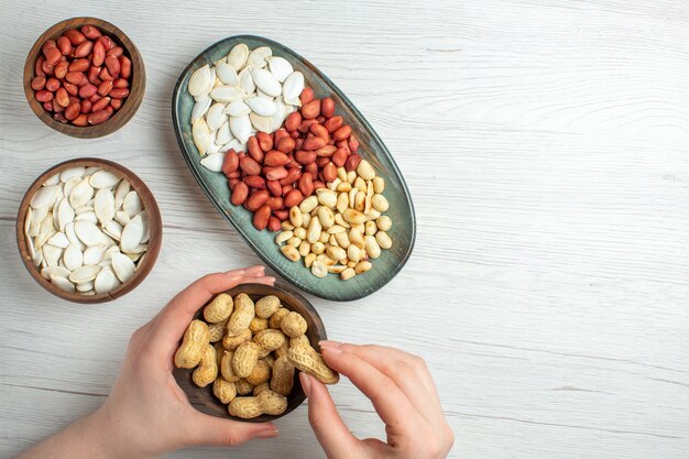 Top view fresh tasty peanuts with white seeds and hazelnuts on white table