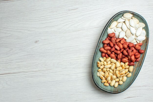 Top view fresh tasty peanuts with white seeds inside plate on white table