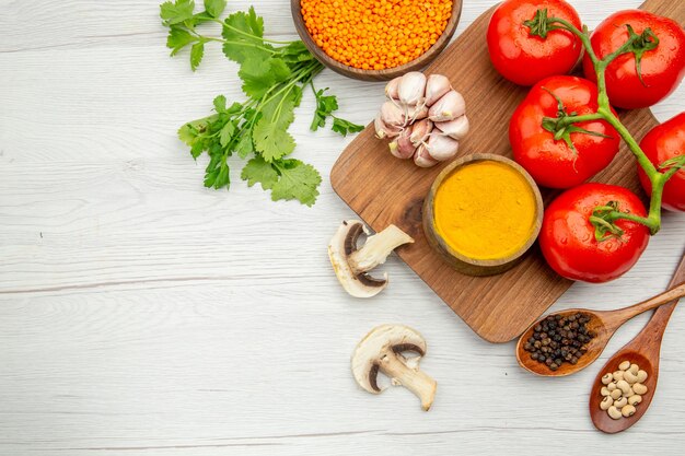 Top view fresh tomato branch garlic turmeric bowl on chopping board mushrooms lentile bowl parsley on grey table