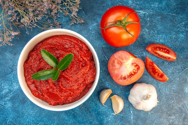 Top view fresh tomatoes with tomato paste and garlic on a blue table