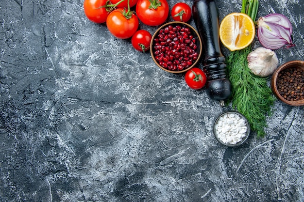 Free Photo top view fresh vegetables bowls with pomegranate seeds sea salt black pepper onion garlic dill on grey background copy space