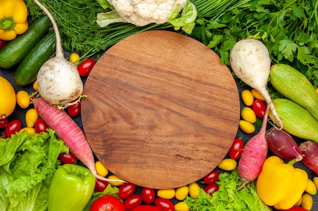 Top view fresh vegetables cherry tomatoes cumcuat lettuce dill yellow bell pepper cucumber zucchini round wood board in center