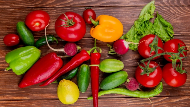 Top view of fresh vegetables colorful bell peppers radish cucumbers tomatoes red chili peppers and lettuce on wood rustic