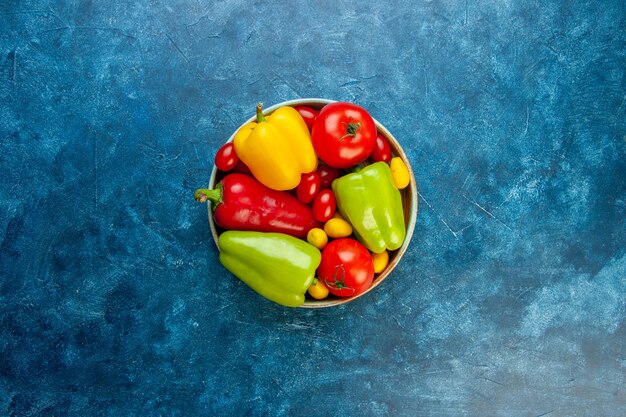 Free Photo top view fresh vegetables different colors bell peppers tomatoes cherry tomatoes in bowl on blue table with copy space