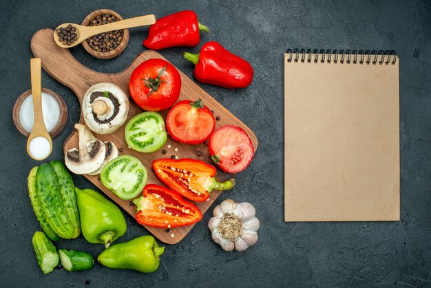 Top view fresh vegetables mushrooms red and green tomatoes bell peppers on chopping board