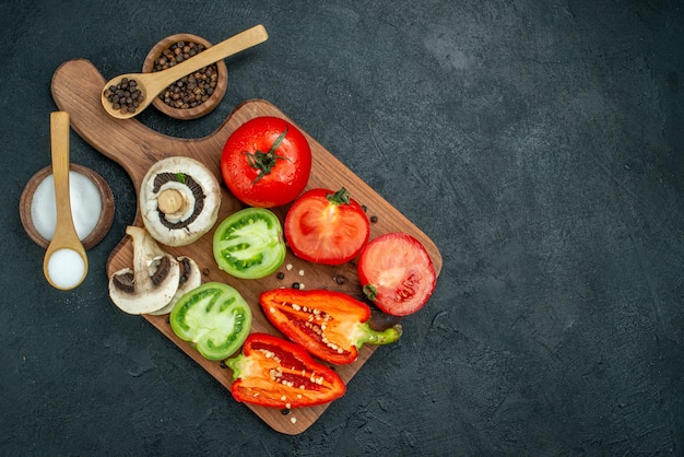 Top view fresh vegetables mushrooms red and green tomatoes bell peppers on cutting board