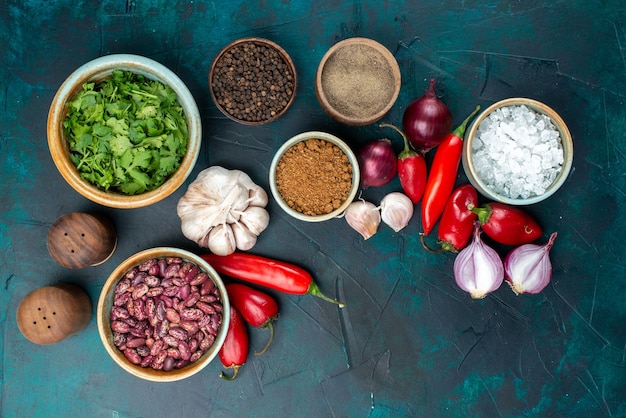 Free photo top view of fresh vegetables onions peppers garlics greens and seasonings on dark-blue desk, vegetable food meal pepper