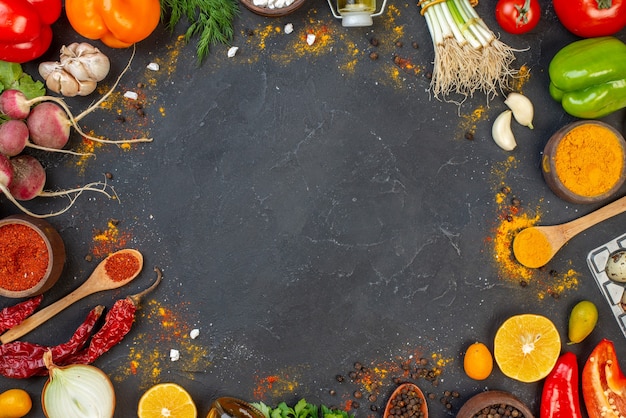 Top view fresh vegetables red pepper powder and turmeric in small bowls wooden spoons on table free space