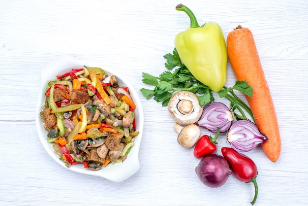 Top view of fresh vegetables such as carrot onions greens and green bell-pepper with meat slices on light desk, vegetable food meal vitamine