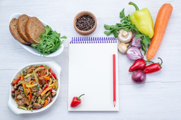 Top view of fresh vegetables such as carrot onions greens and green bell-pepper with meat slices on light floor, vegetable food meal vitamine meat