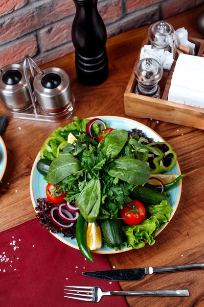 Top view of fresh vegetables tomato cucumber red onion and herbs on a wooden table