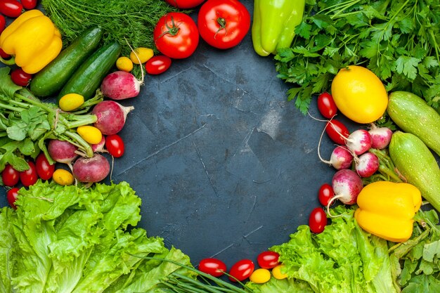 Top view fresh vegetables tomatoes lettuce radish lemon zucchini parsley cherry tomatoes on dark surface free space in center