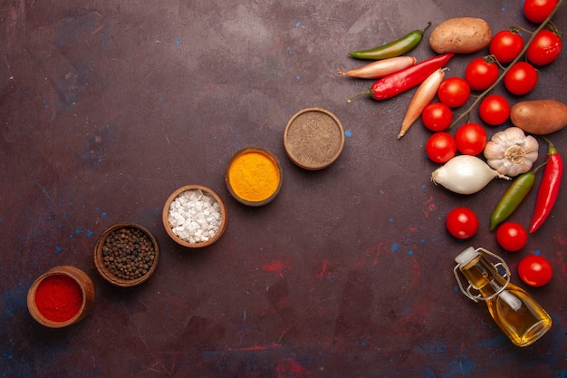 Top view fresh vegetables with different seasonings on dark space