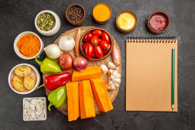 Top view fresh vegetables with pumpkin seasonings and seeds on dark background salad ripe meal color