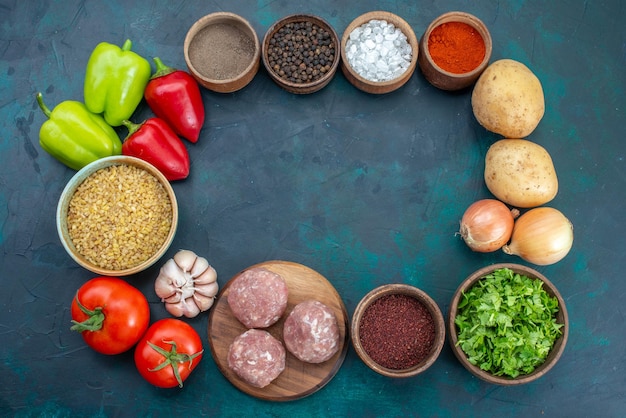 Free photo top view fresh vegetables with seasonings and greens on the dark-blue surface