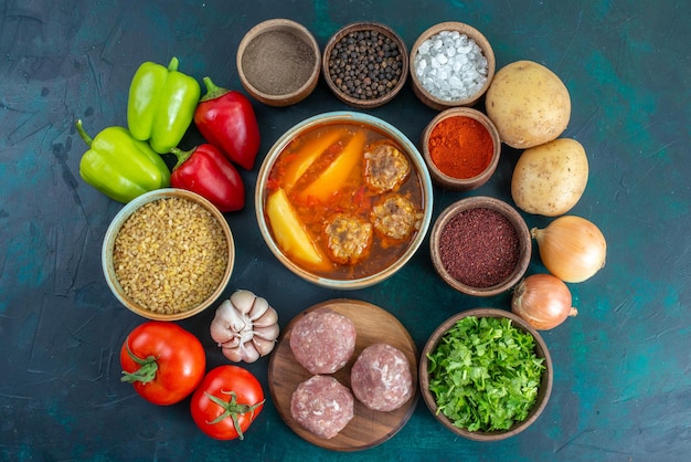 Top view fresh vegetables with seasonings meat soup and greens on the dark blue surface