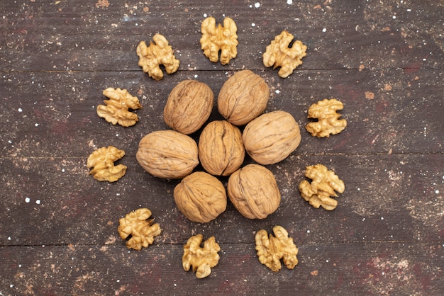 Top view fresh whole walnuts inside shell and cleaned out lined on brown